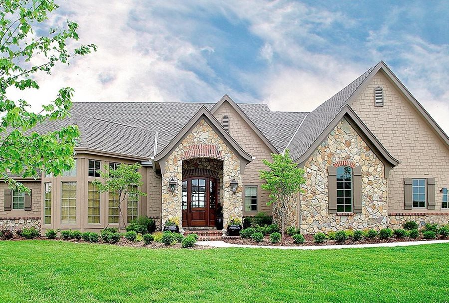 A french country house with shake siding and rustic cut brown stone