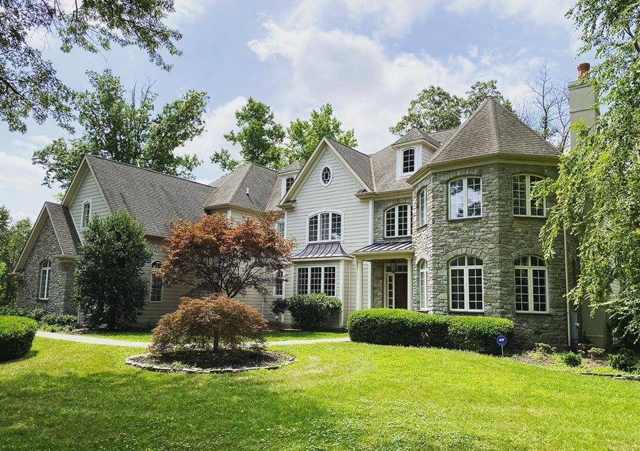 A two-story house in a neutral color palette with light cream siding and gray-toned stone