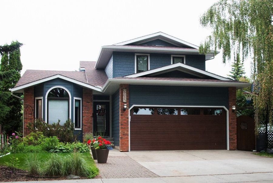 A house with dark blue plank siding with red brick accents