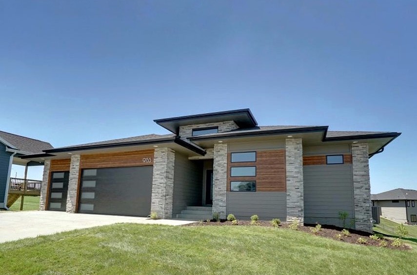 Modern home exterior featuring white and grey color scheme with black accents, flat rooflines, large windows, and clean geometric shapes