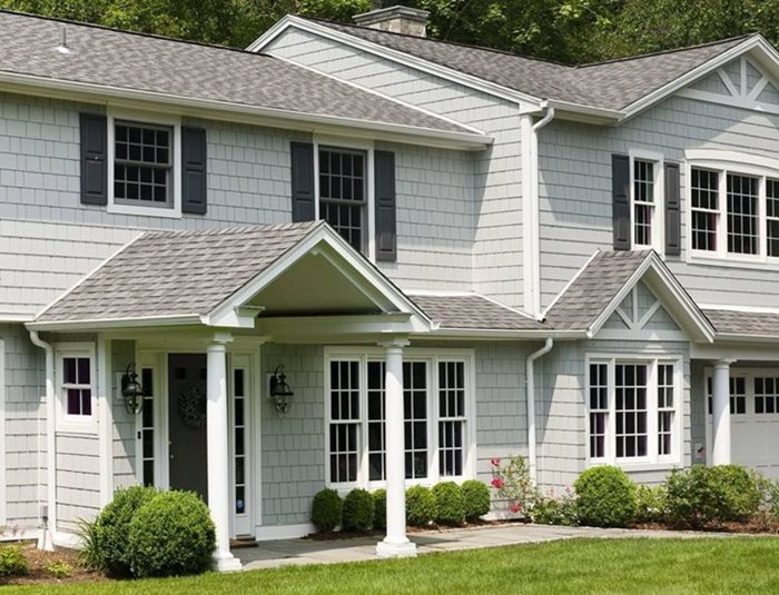 Section of a building's exterior featuring shingle siding made up of small rectangular pieces of material overlaid in an overlapping pattern